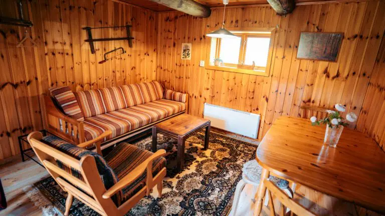 intérieur chaleureux d’une cabane en bois avec canapé rayé et table à manger