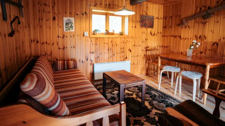 intérieur chaleureux d’une cabane de bûcheron aux murs en bois avec un canapé rayé