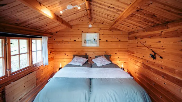 intérieur chaleureux d’une cabane en bois avec deux lits jumeaux et une canne à pêche