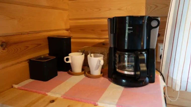 machine à café et tasses sur un tapis rayé dans un chalet en bois