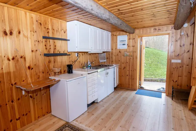 intérieur chaleureux d’une cabane de bûcheron avec une petite cuisine et des murs en bois