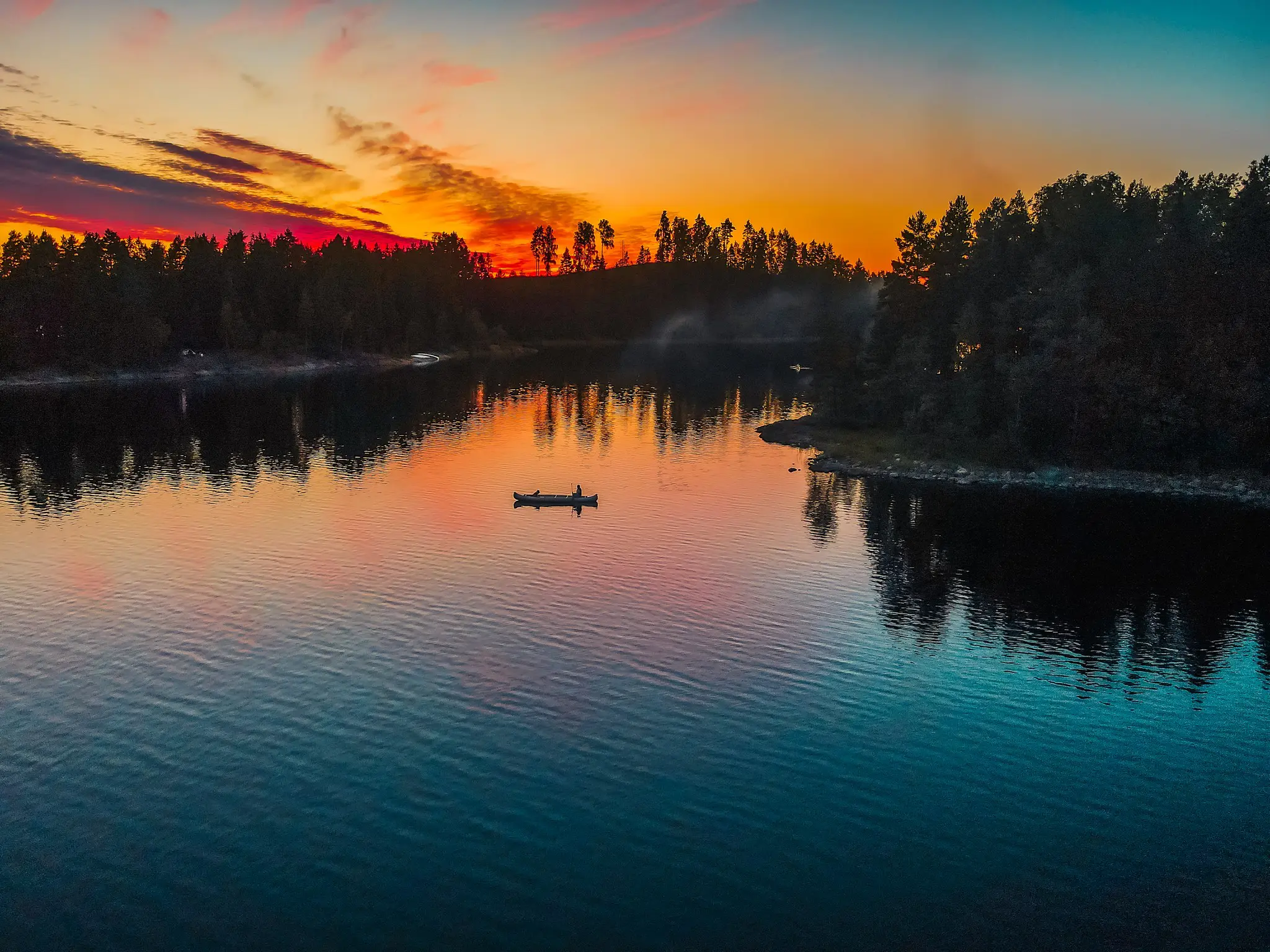 canoë sur un lac au coucher du soleil, entouré de forêt