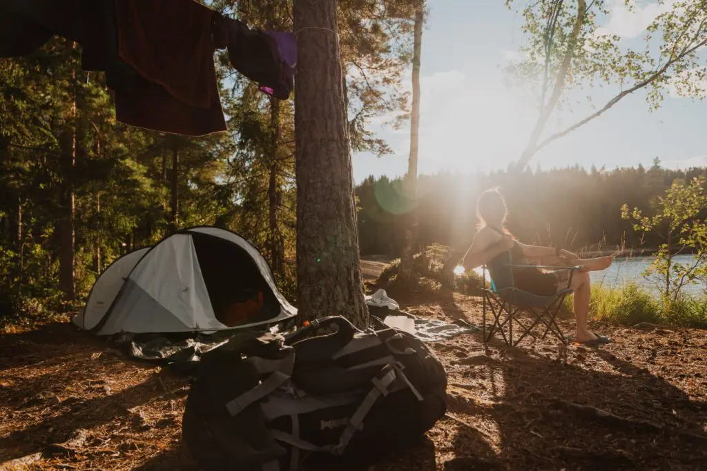 personne se détendant dans un camping au bord d’un lac au coucher du soleil