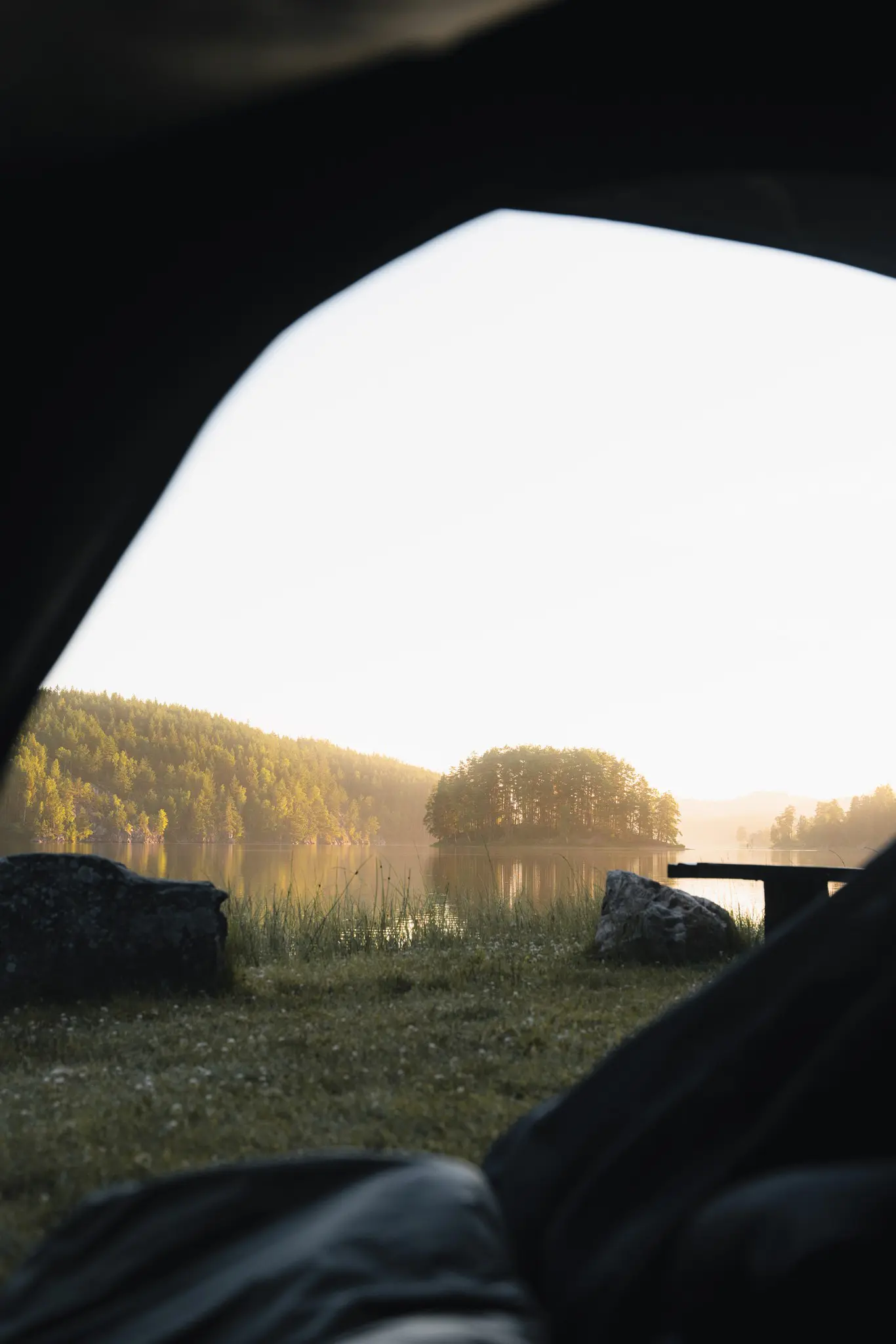 vue depuis l'intérieur d'une tente donnant sur un lac au lever du soleil
